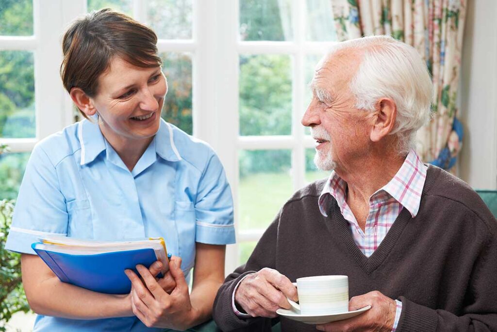 Older adult arranging family photos and a favorite blanket in a comfortable assisted living room.